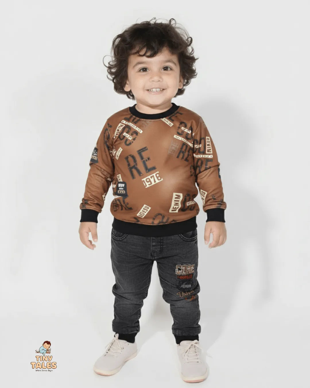 Child wearing a brown sweater with text patterns and dark jeans on a white background