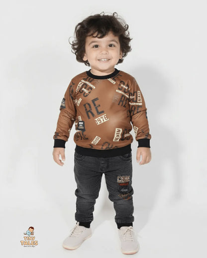 Child wearing a brown sweater with text patterns and dark jeans on a white background