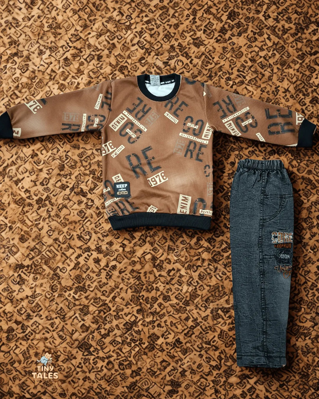 Children's brown sweater with text pattern and blue jeans on a textured brown background