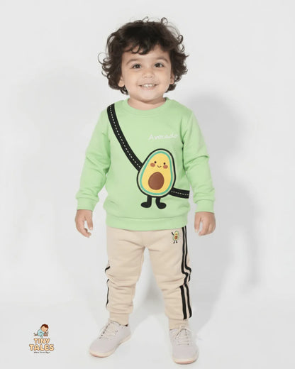Child wearing a green sweatshirt with an avocado design and beige pants on a white background