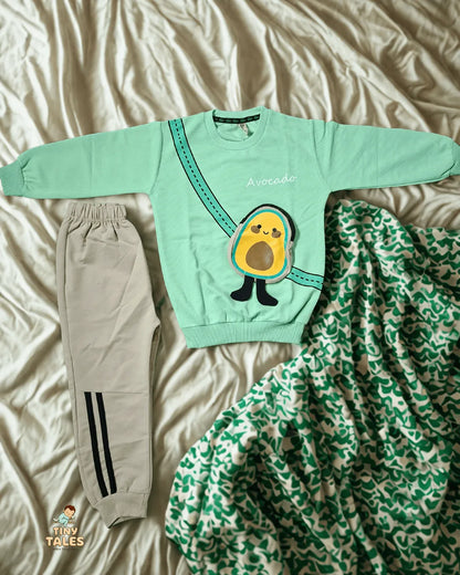 Light green sweatshirt with avocado design and matching pants on a bed