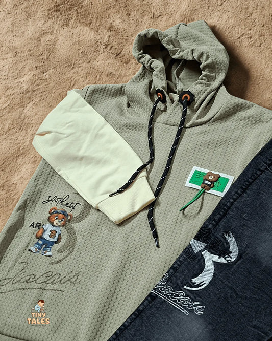 Green hoodie with embroidered designs on a textured surface