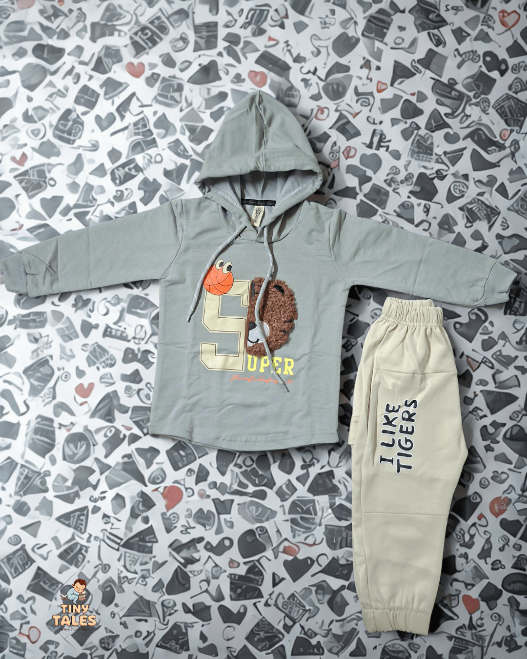 Children's hoodie and pants set on a patterned surface. Tiny Tales baby clothing, Organic baby clothes Pakistan, Premium baby wear, Soft cotton baby rompers, Newborn and toddler outfits, Baby dresses and essentials, Eco-friendly baby fashion, Cute baby clothes online, Safe baby clothing brand, Tiny Tales baby shop