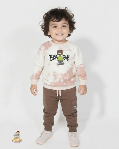 Child wearing a tie-dye sweatshirt with a graphic design and brown pants on a white background