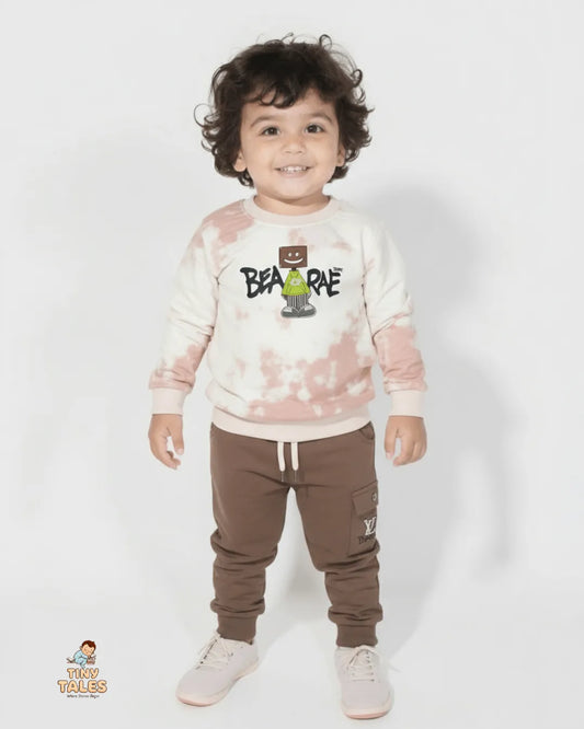 Child wearing a tie-dye sweatshirt with a graphic design and brown pants on a white background