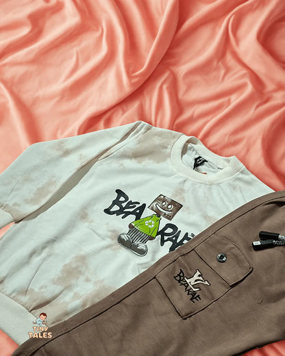 White t-shirt with graphic design and brown pants on a pink fabric background