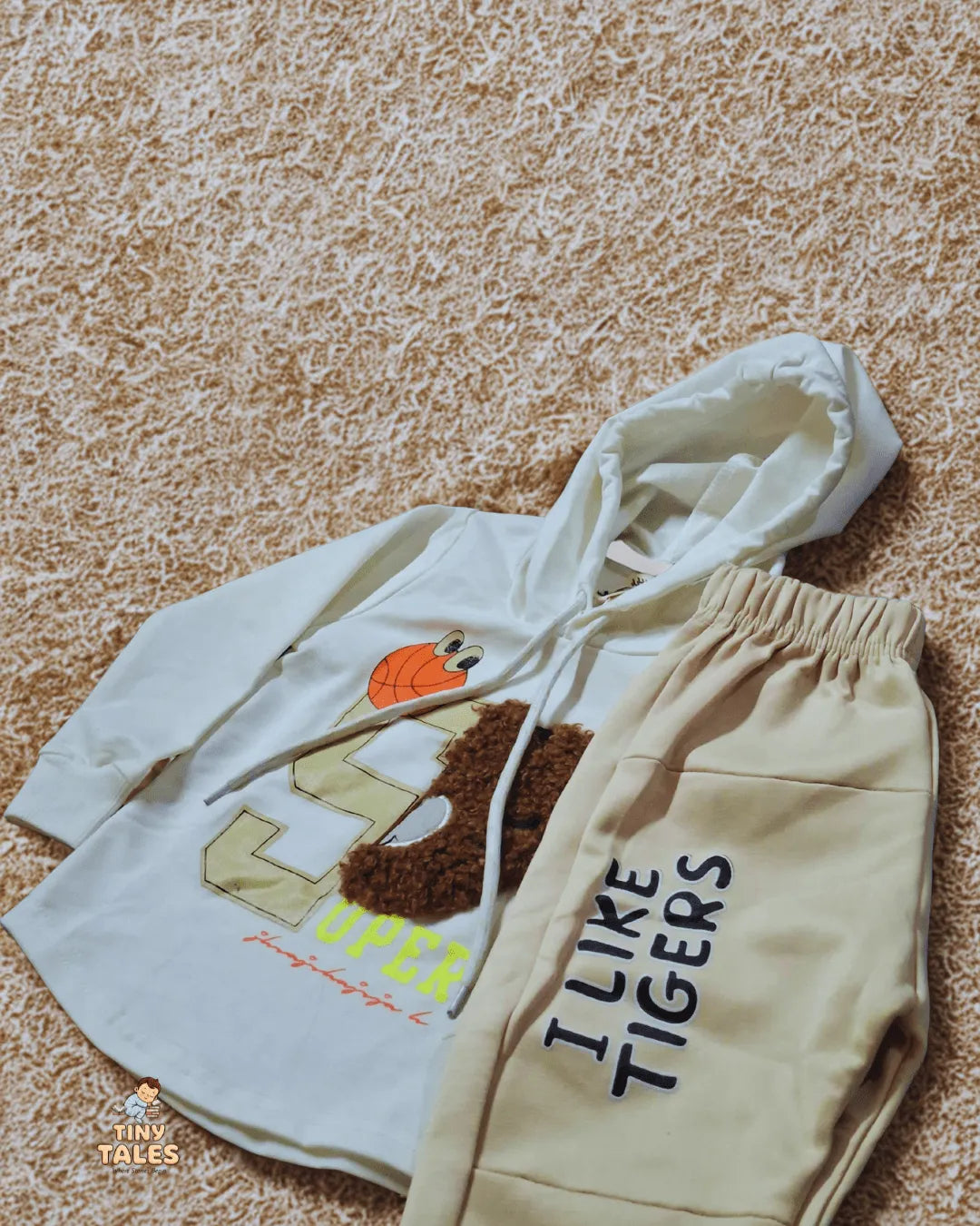 Children's hoodie and pants set with tiger design on a textured surface