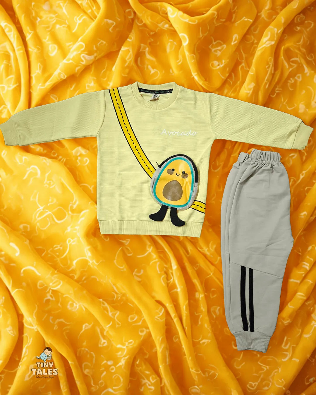 Children's sweatshirt with cartoon design and gray pants on a yellow fabric background