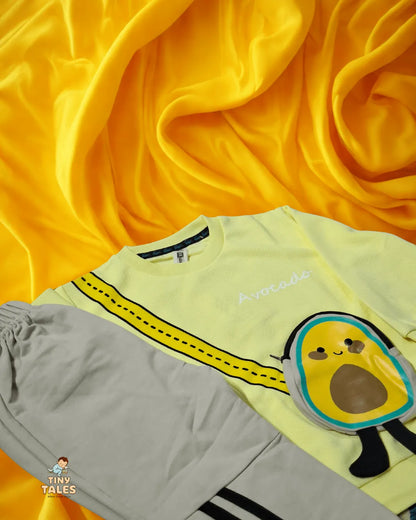 Light green t-shirt with avocado design and gray shorts on a yellow fabric background
