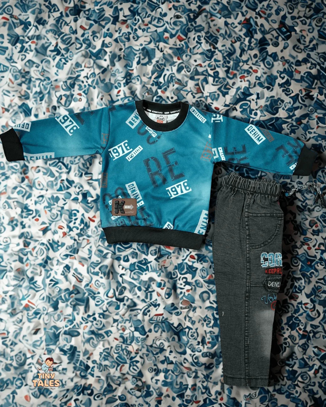 Children's blue sweatshirt and gray pants on a patterned surface